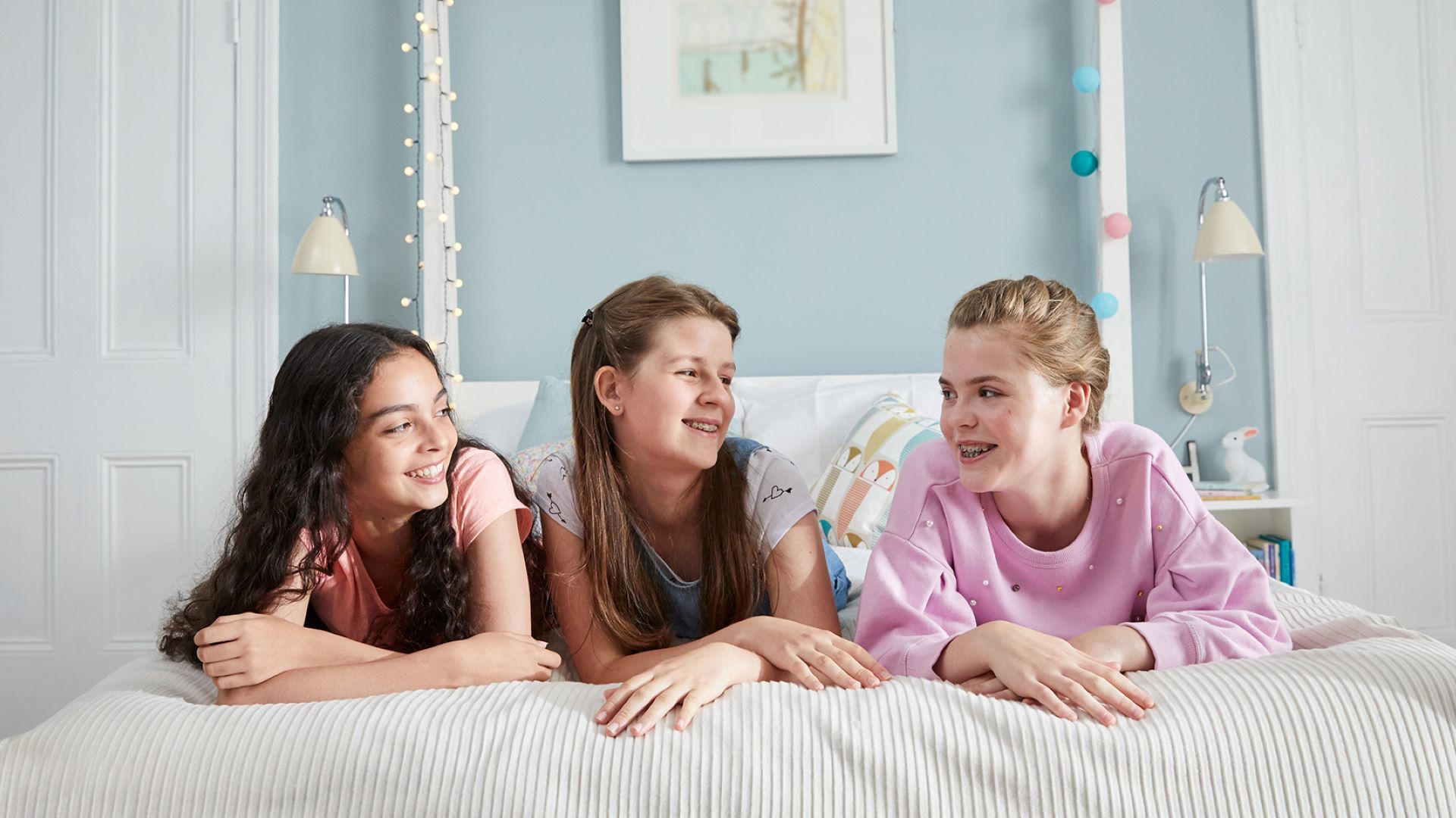 Drie gelukkige meisjes in een slaapkamer.