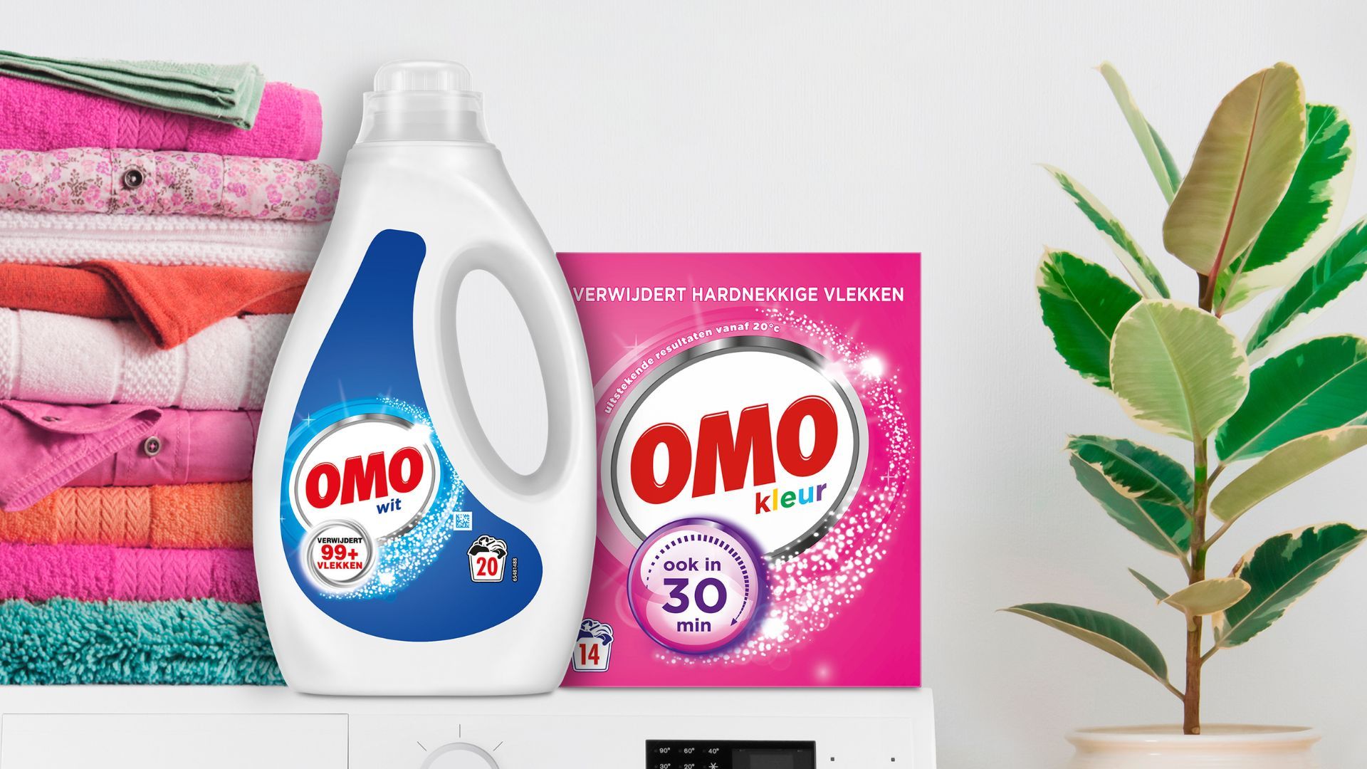 Op de banner zie je een wasmachine met daarop verschillende kledingstukken opgevouwen. Ook staat er een fles OMO Wit Vloeibaar wasmiddel en een doos OMO Kleur waspoeder op.